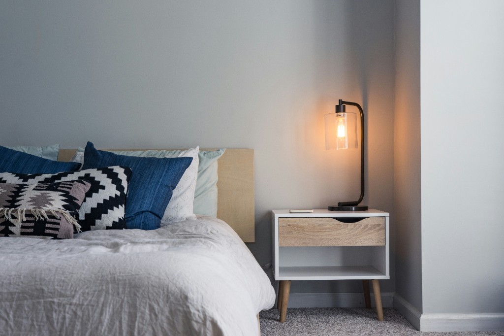 Cozy bedroom corner with layered pillows and a warm bedside lamp